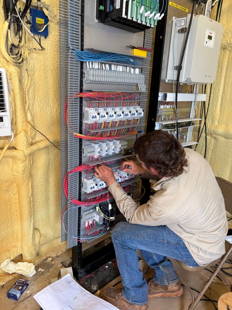 Licensed electrician installing and wiring a commercial electrical control panel.